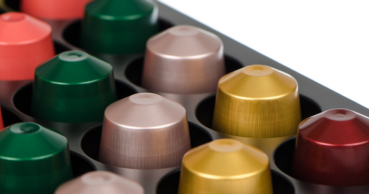 Assorted colorful Nespresso compatible coffee capsules arranged neatly in capsule holder tray.
