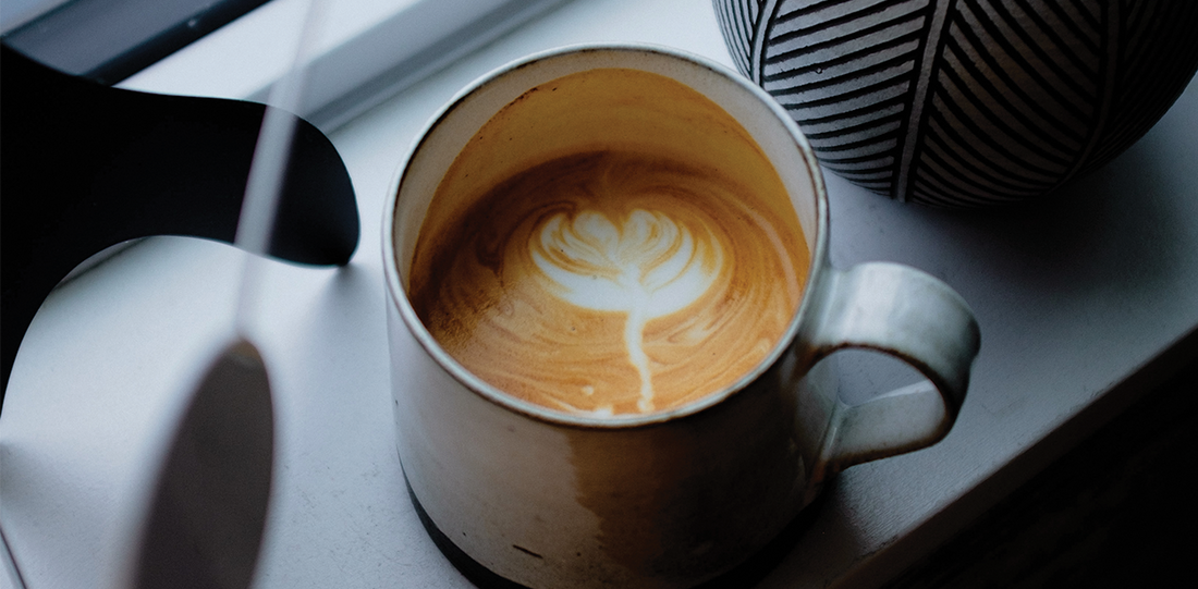 Creamy latte with latte art placed near a window, capturing a peaceful winter morning coffee ritual with natural light.