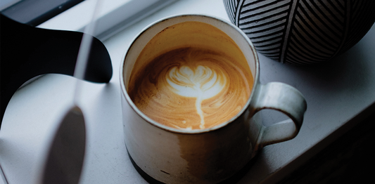 Creamy latte with latte art placed near a window, capturing a peaceful winter morning coffee ritual with natural light.