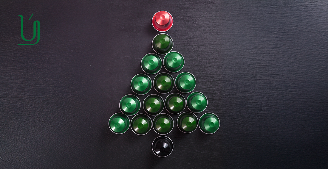A festive Christmas tree shape created using green and black Nespresso-style coffee capsules, topped with a red capsule, displayed on a dark background with the Yasma Coffee logo.