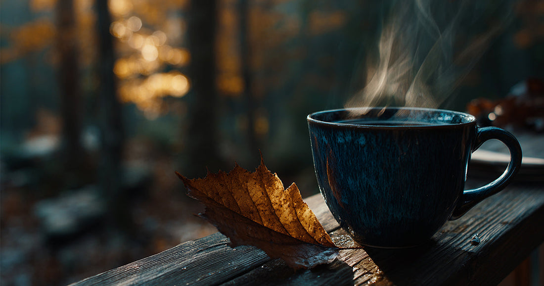 A steaming blue mug with an autumn leaf on a wooden surface, evoking the peaceful beauty of crisp fall mornings.
